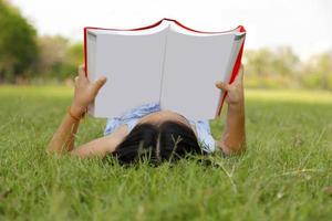 Aziatisch klein meisje leesboek in het park foto
