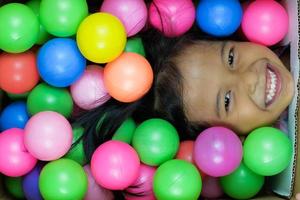 een meisje dat breed lacht en speelt in de kleurrijke bal foto