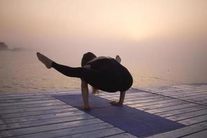 jonge vrouw poseren in yoga asans, ochtend zee achtergrond foto