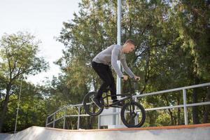 bmx-rijderstraining en trucs doen op straatplein, fietsstuntrijder in cocncrete skatepark foto