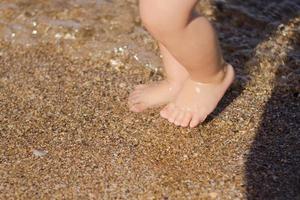 close-up foto van vader met een kind van een jaar dat 's zomers op het strand loopt