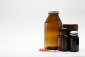 roze, groene en rode tabletten op een witte achtergrond met amberkleurige medicijnflescontainer. lichtbestendige verpakking. farmaceutische industrie. vitamine en supplement product. kleurrijke pillen en medicijnpotten. foto