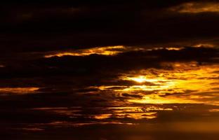 mooie zonsonderganghemel. gouden zonsonderganghemel met mooi patroon van wolken. oranje, geel en donkere wolken in de avond. vrijheid en rustige achtergrond. schoonheid in de natuur. krachtige en spirituele scène. foto