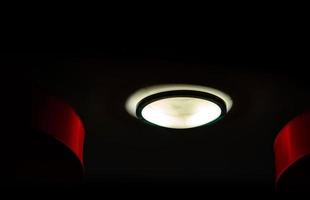 interieur plafondverlichting op donkere achtergrond 's nachts. interieur verlichtingsconcept. rond glas met zwarte ringkap plafondlamp. foto