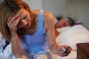 een vrouw die lijdt aan slapeloosheid terwijl haar man slaapt foto