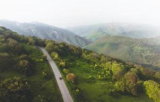 luchtfoto vogels eye view van auto op asfaltweg in schilderachtige kaukasische bergen. reizen in Georgië foto