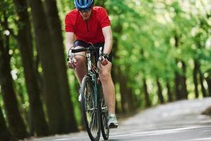 fitness dag. fietser op een fiets is op de asfaltweg in het bos foto