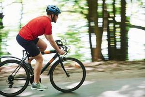 fijn gevoel. fietser op een fiets is op de asfaltweg in het bos op zonnige dag foto