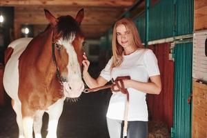 binnenkant van het gebouw. gelukkige vrouw met haar paard overdag op de ranch foto