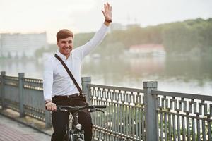 Leuk je te zien. zakenman in formele kleding met zwarte fiets is in de stad foto