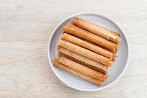 wafel loempia's of semprong cake, een traditionele Indonesische snack met een unieke vorm als een gelaagde pijp, geserveerd op een wit bord. geselecteerde focus. foto