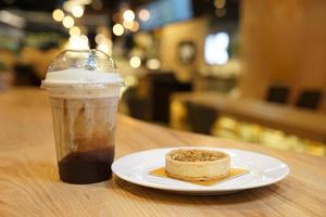 notenkaramel maancake met ijs latte koffie ernaast, op de houten tafel. foto