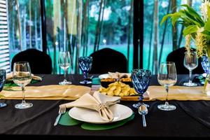 luxe lunch- of dinerset op het lange tafelpatroon met een zwarte dektafel met bloemdecoratie. foto