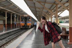 gelukkige Azië-vrouwenreiziger die geluk voelt voordat hij gaat reizen op het treinstation, zomerreizen en lifestyle-concept foto