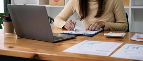 financiële zakenmensen of accountants wijzen naar de grafiek en gebruiken een rekenmachine om bedrijfsinkomsten, uitgaven, belastingen en werknemersbonussen te berekenen. boekhoudkundig financieel concept foto