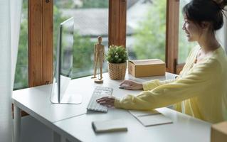 lachende jonge freelance zakenvrouw met behulp van desktop-pc op kantoor. foto