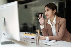 jonge aziatische zakenvrouw werkt thuis en virtuele videoconferentievergadering met collega's zakenmensen, online werken, videogesprek vanwege sociale afstand thuiskantoor foto