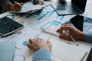 twee zakelijke collega's ontmoeten elkaar om te brainstormen over het nieuwe project bedrijfsstrategieplan en analysegegevensdocument, financiën en boekhoudconcept. close-up hand met rekenmachine foto