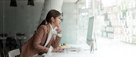 zijaanzicht van zakelijke Aziatische vrouw of accountant werkende computer op kantoor foto