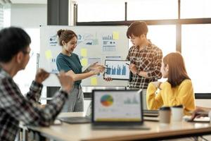 diverse collega's samenwerkend brainstormen tijdens kantoorbriefing. jonge zakenman en vrouw die analyse uitleggen tijdens het opstartwerk van de vergadering. foto