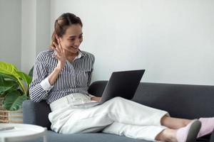 technologie, vrije tijd en mensen concept - gelukkig lachende vrouw met laptopcomputer met videochat en zwaaiende hand thuis. foto