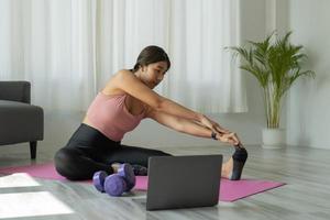 jonge vrouw oefent thuis yoga uit. fitness, training, gezond leven en dieetconcept foto