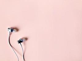 witte oortelefoon op pastelroze kleur achtergrond zomer foto
