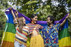 groep transgender en homoseksuele mensen die lgbtq-trotsmaand vieren in kleurrijke jurk en regenboogvlag met positieve sfeer, lachen en plezier foto