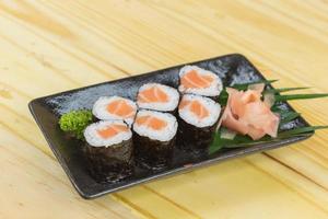 sushi maki met zalm in een witte plaat op een houten vloer foto