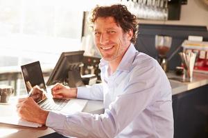 mannelijke restaurantmanager die op laptop werkt foto