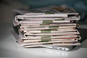 stapel kranten, geplaatst op een laptop foto