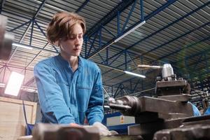 professionele jonge blanke vrouwelijke industrie-ingenieurswerknemer werkt in veiligheidsuniform met precisiegereedschappen voor metaalbewerking, mechanische draaimachines en werkplaats voor reserveonderdelen in de staalfabriek. foto