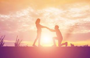 een silhouet van een man en vrouw hand in hand met elkaar, samen wandelen. foto