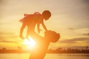 vader nam de baby leren lopen bij zonsondergang. foto