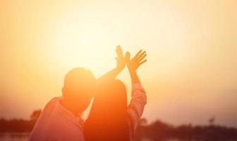 een silhouet van een man en vrouw hand in hand met elkaar, samen wandelen. foto