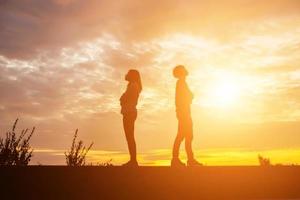 een silhouet van een man en vrouw hand in hand met elkaar, samen wandelen. foto