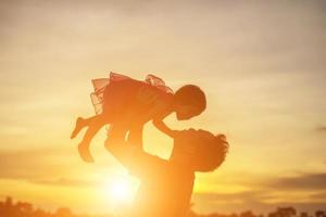 vader nam de baby leren lopen bij zonsondergang. foto