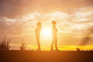 een silhouet van een man en vrouw hand in hand met elkaar, samen wandelen. foto