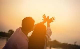 een silhouet van een man en vrouw hand in hand met elkaar, samen wandelen. foto