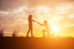 een silhouet van een man en vrouw hand in hand met elkaar, samen wandelen. foto