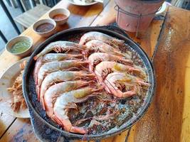 Gegrilde garnalen op een hete pan op een houten tafel foto