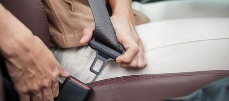 vrouw bestuurder hand vastmaken veiligheidsgordel tijdens het zitten in een auto en rijden op de weg. veiligheids-, reis-, reis- en transportconcept foto