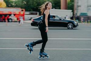 skate-concept. actieve fit jonge vrouw rijdt op schaatsen langs drukke weg met transportbewegingen heeft actief haar dat op de wind drijft, in goede fysieke conditie is, geniet van rust en recreatie. foto
