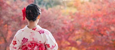 jonge vrouwentoerist die kimono draagt genietend van met kleurrijke bladeren in de tempel van kiyomizu dera, kyoto, japan. Aziatisch meisje met haarstijl in traditionele Japanse kleding in het herfstgebladerteseizoen foto