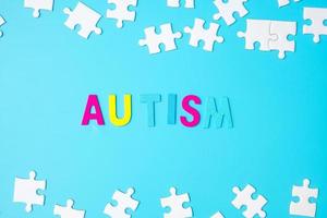 autisme tekst met witte puzzelstukjes op blauwe achtergrond. concepten van gezondheid, autistische spectrumstoornis en wereld autisme bewustzijnsdag foto