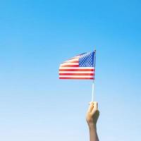hand met de vlag van de Verenigde Staten van Amerika op blauwe hemelachtergrond. usa vakantie van veteranen, gedenkteken, onafhankelijkheid en dag van de arbeid concept foto