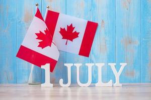 houten kalender van 1 juli met miniatuur canada vlaggen. Canada Day en gelukkige vieringsconcepten foto