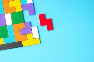 kleurrijke houten puzzelstukjes op blauwe achtergrond, geometrische vorm blok. concepten van logisch denken, raadsel, oplossingen, rationeel, strategie, wereldlogicadag en onderwijs foto