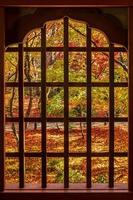 frame tussen houten raam en prachtige esdoorn in japanse tuin bij enkoji-tempel, kyoto, japan. mijlpaal en beroemd in het herfstseizoen foto