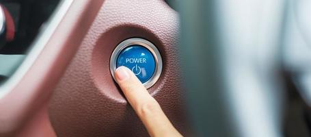 vinger druk op een auto-ontstekingsknop of start de motor in een moderne elektrische auto. keyless, verandering, strategie, visie, innovatie en toekomstconcept foto